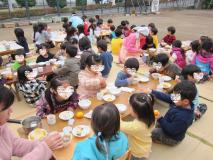 園庭ですいとんを食べている写真です