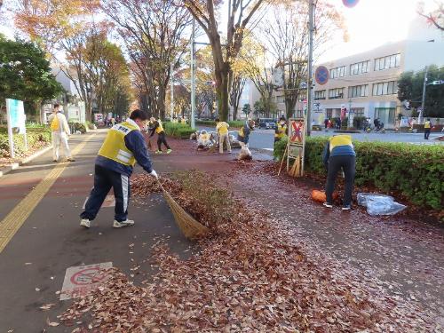 箒で落ち葉を集める市長の様子